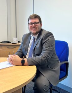 Tindles Careers: Tindles new hire, Adam, sat at a desk smiling as he starts his new career at the firm.